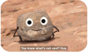 a cartoon stone talking to the camera on a red rocky floor